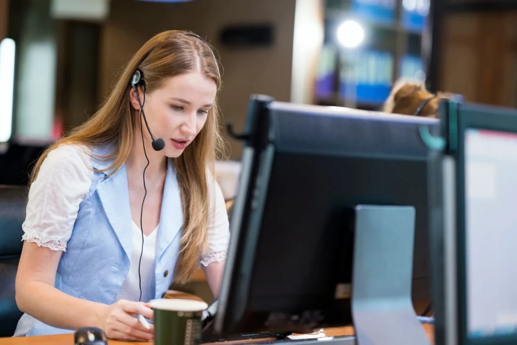 A call center agent wearing a headset works at her computer