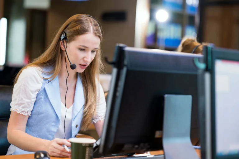 A call center agent wearing a headset works at her computer