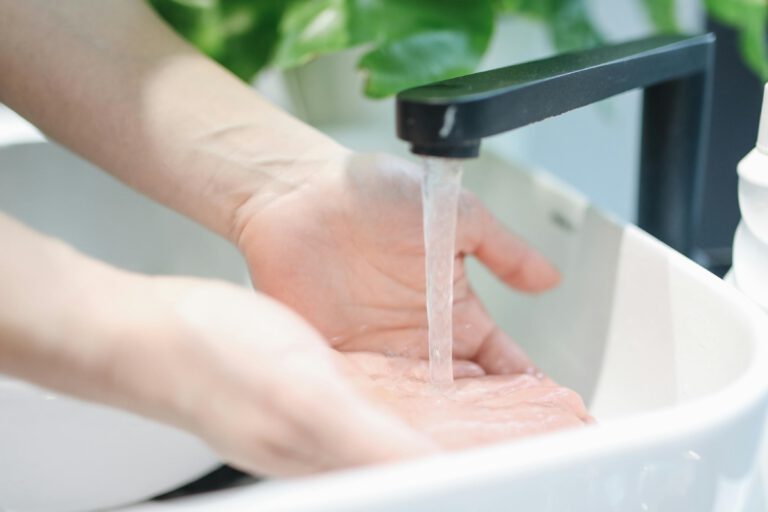 A person washing their hands under a running faucet