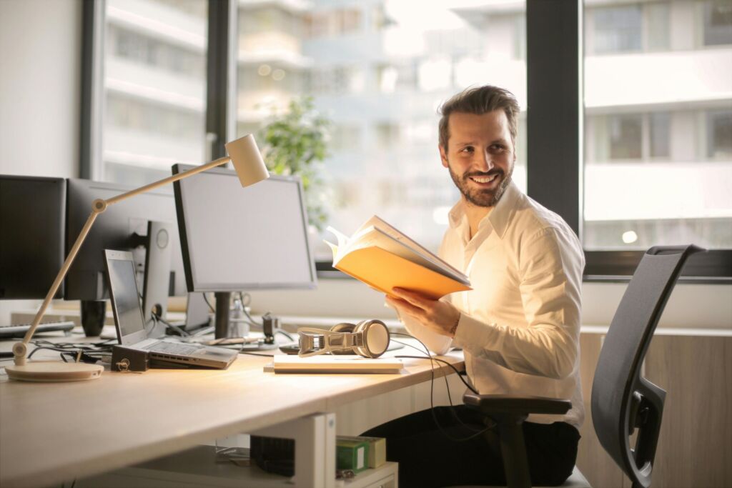 man holding pamphlet while sitting at his desk