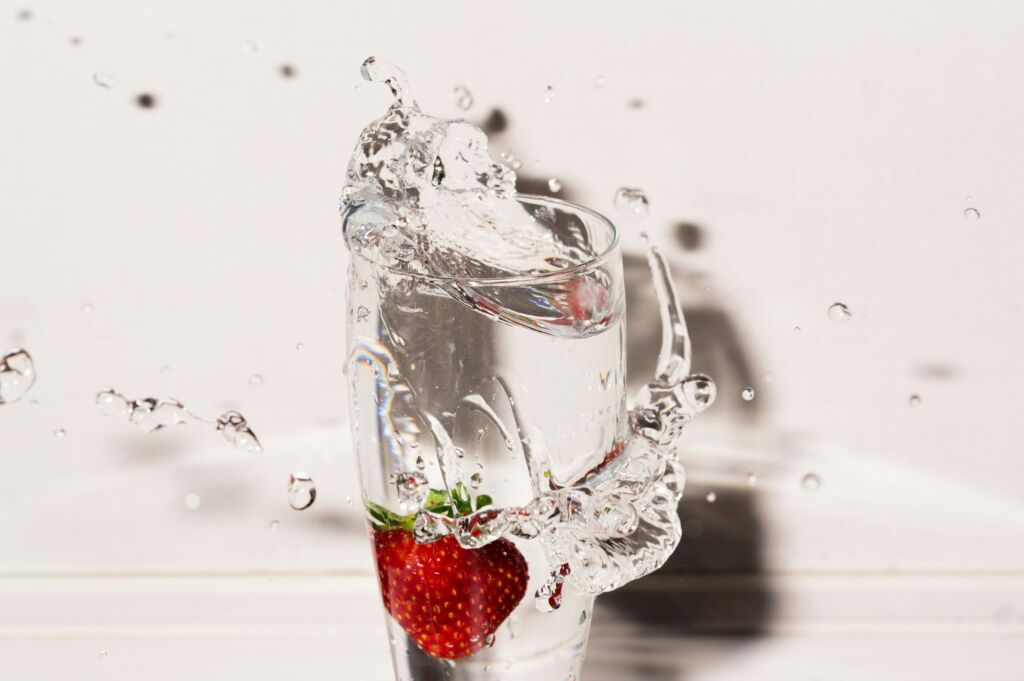 A strawberry splashing into a glass of water