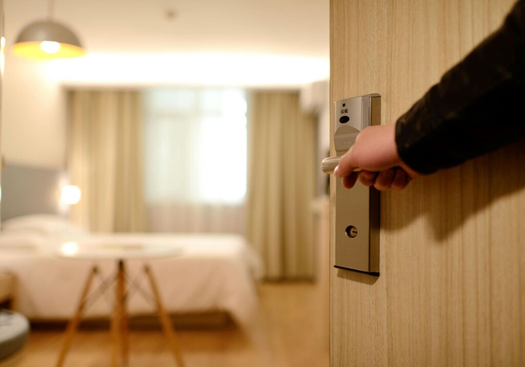 A hand opening the door to a hotel room