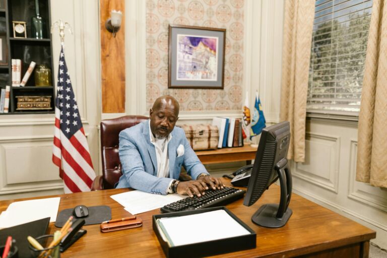 A man working at a desk in an office with an American flag