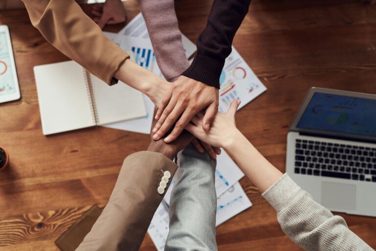 A team joining hands together over a desk