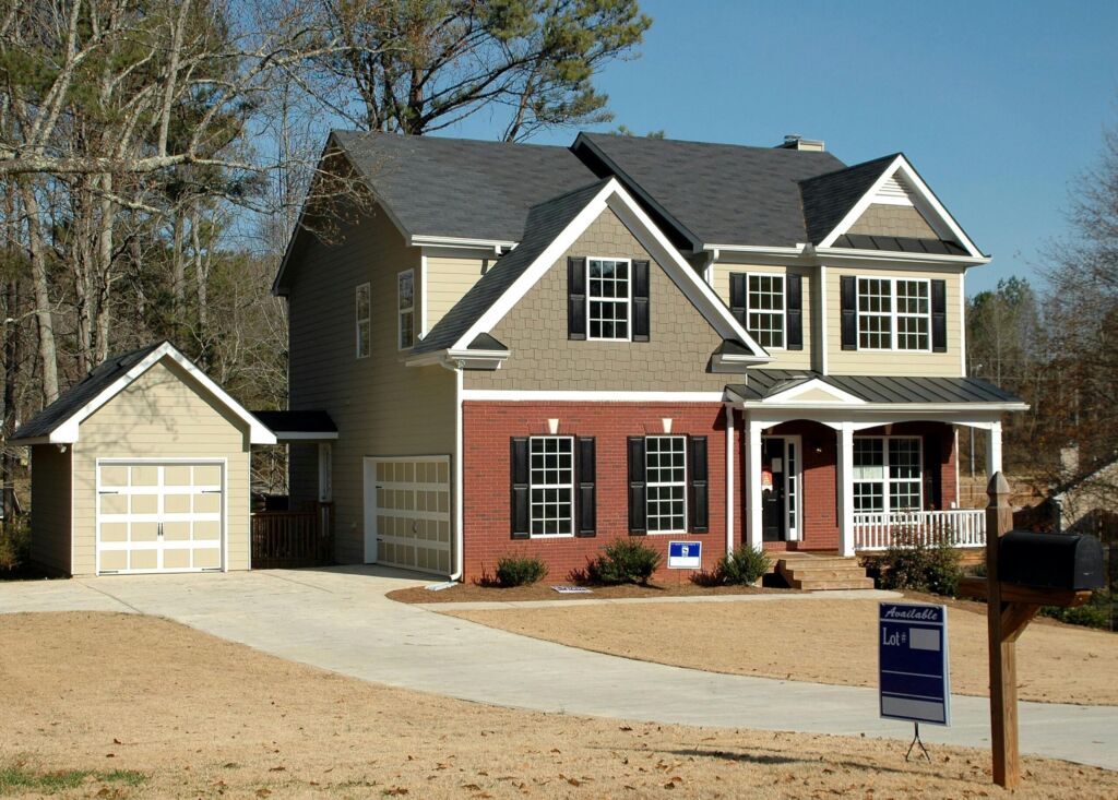 A two-story suburban home with a for-sale sign in the yard