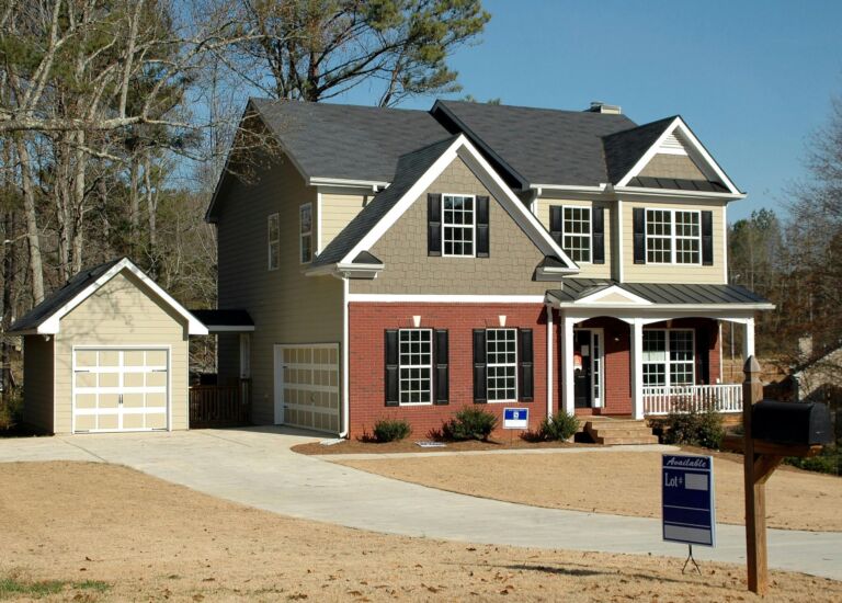 A two-story suburban home with a for-sale sign in the yard