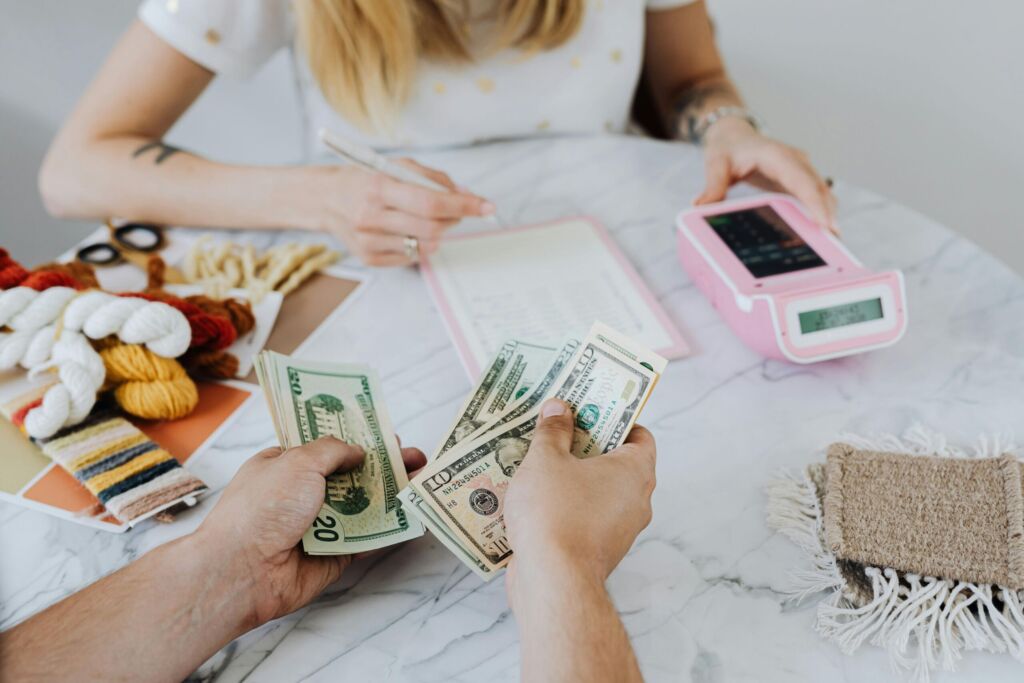 Hands counting US dollar bills at a table