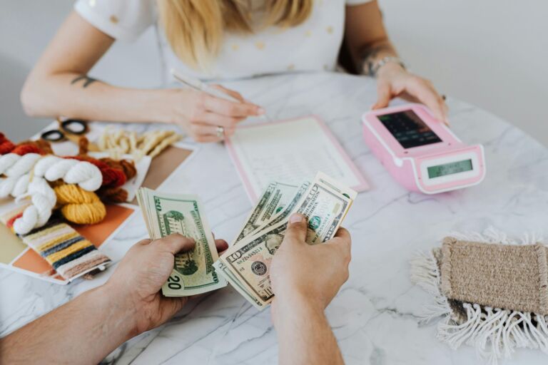 Hands counting US dollar bills at a table