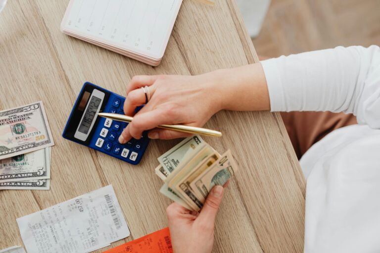 A person counting cash with a calculator and receipts