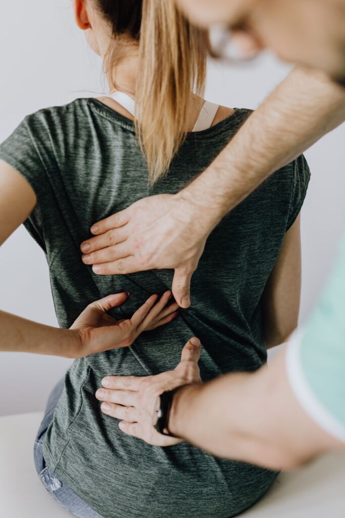 Chiropractor examining the back of a patient in a clinic
