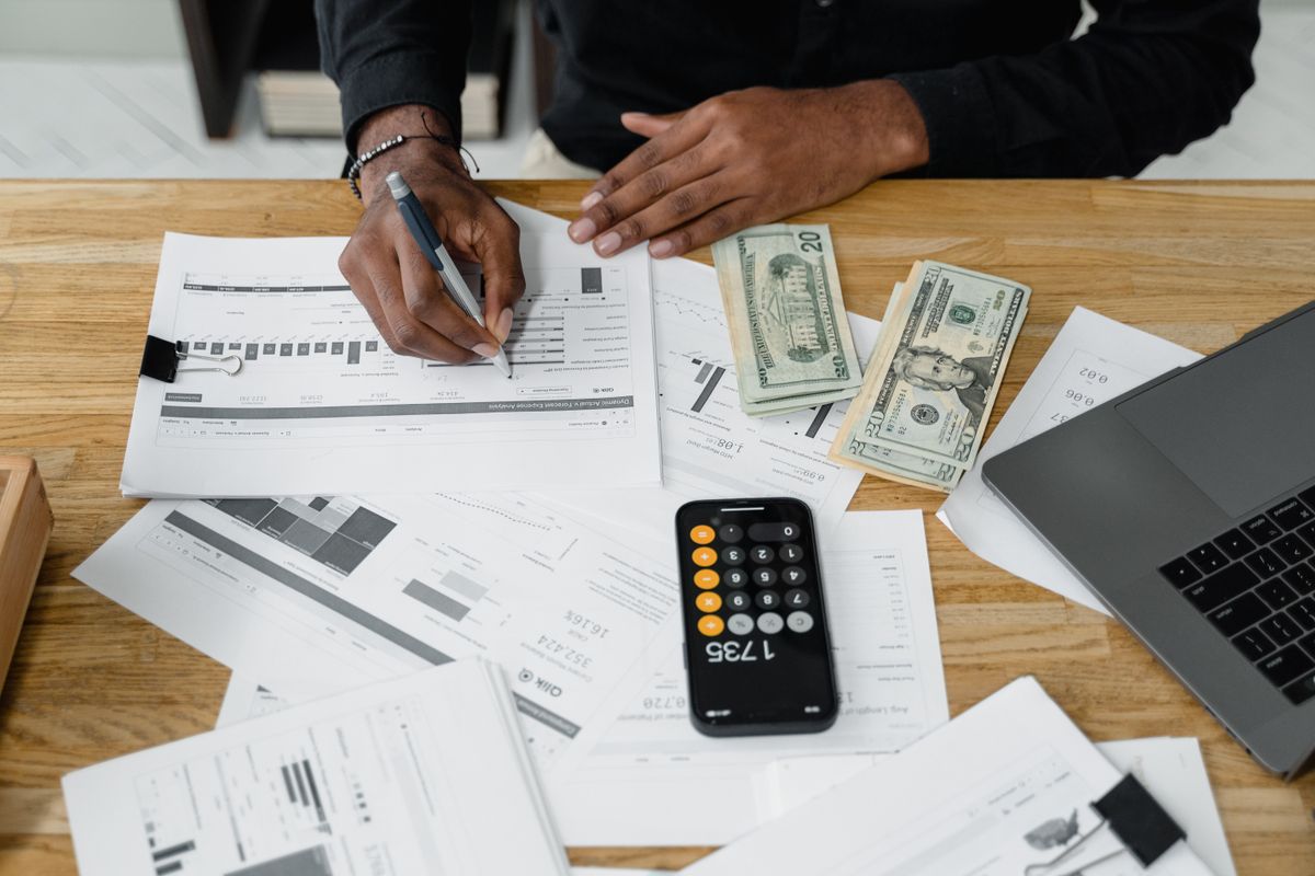 Accountant reviewing financial reports with a calculator and laptop at a desk