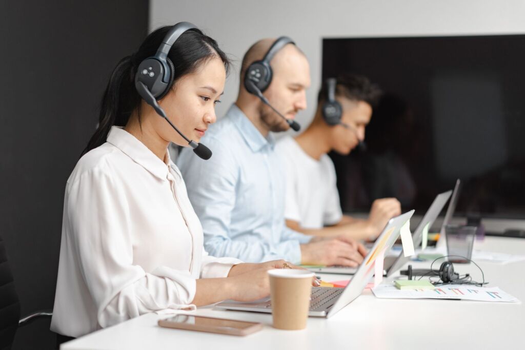 Customer service representative wearing a headset and smiling while answering a call in a modern office