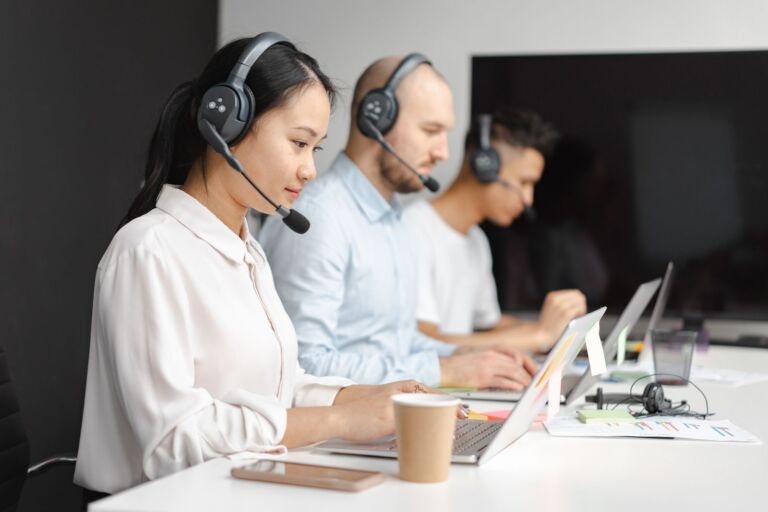 Customer service representative wearing a headset and smiling while answering a call in a modern office