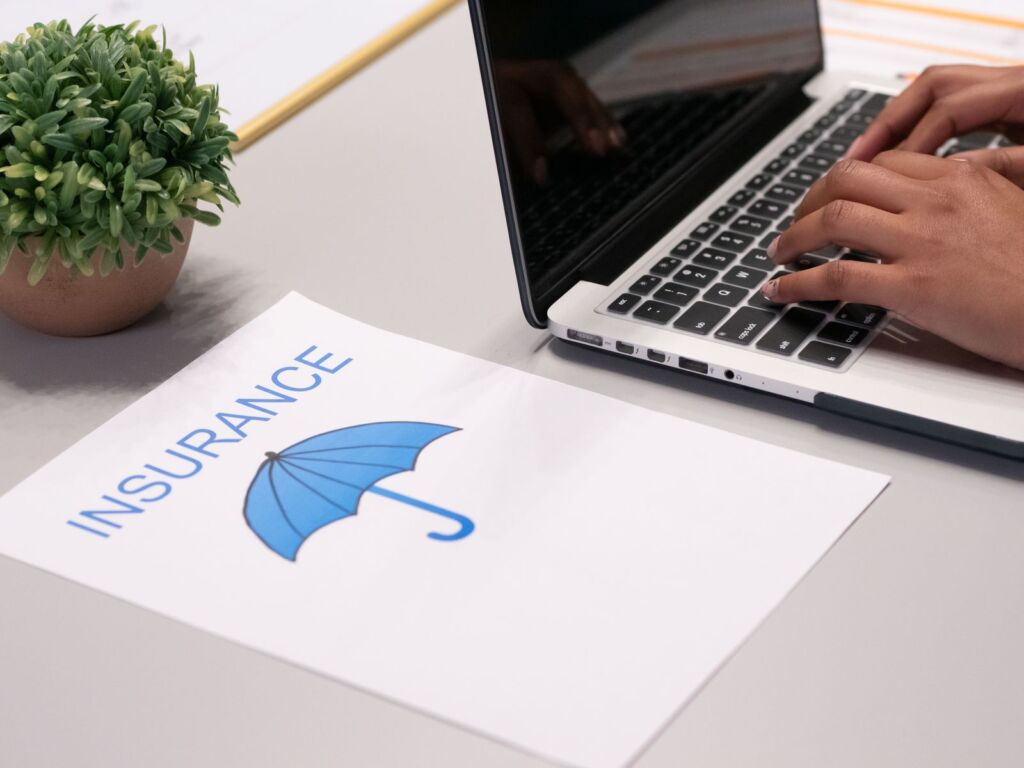 Insurance paperwork beside a person typing on a laptop