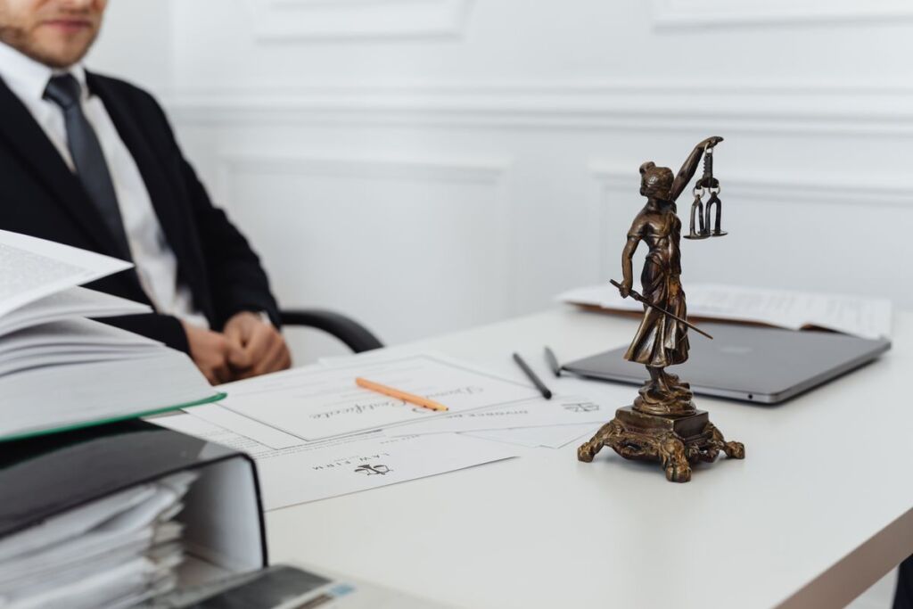 Attorney's desk with a Lady Justice statue, legal documents and a laptop